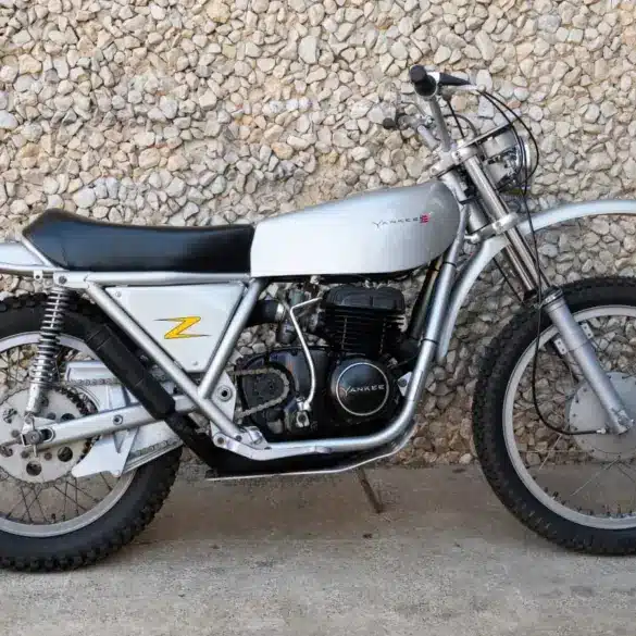 1972 Yankee Z500 Enduro Motorrad in silberner Lackierung seitlich vor einer Steinmauer.