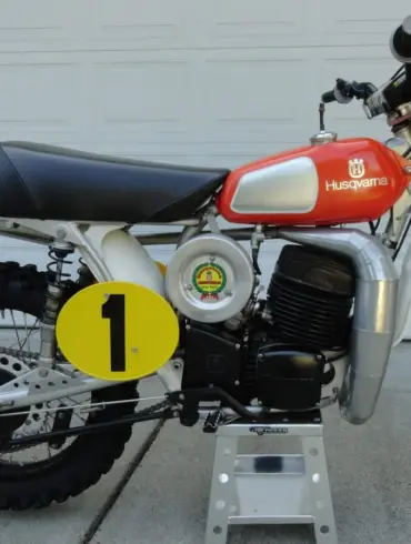 Seitenansicht einer 1974 Husqvarna 400 CR Motocross-Maschine mit rotem Tank und Startnummernschild.