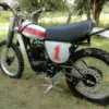 Klassische 1976 Yamaha YZ250C Motocross-Maschine mit Startnummer 1, Seitenansicht auf einer Wiese.
