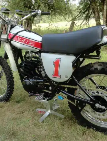 Klassische 1976 Yamaha YZ250C Motocross-Maschine mit Startnummer 1, Seitenansicht auf einer Wiese.