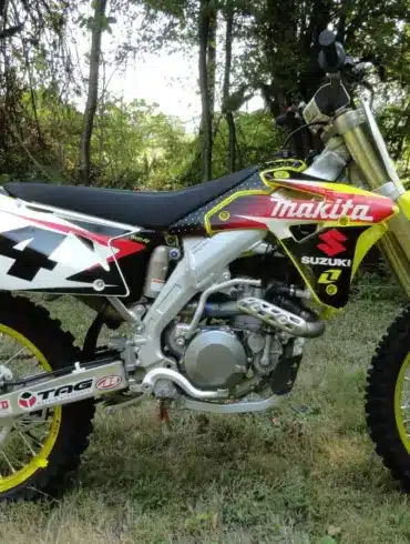 Suzuki RM-Z450 Ricky Carmichael Special Edition 2007 im Makita-Werkstrim auf einer Wiese, linksseitige Ansicht.