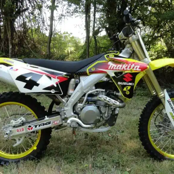 Suzuki RM-Z450 Ricky Carmichael Special Edition 2007 im Makita-Werkstrim auf einer Wiese, linksseitige Ansicht.