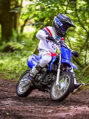 Jugendlicher auf einer Yamaha TT-R110 fährt Offroad durch einen Wald