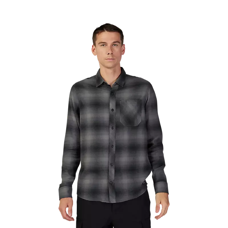Mann trägt ein schwarzes Survivalist Flanellhemd mit Brusttasche vor weißem Hintergrund.