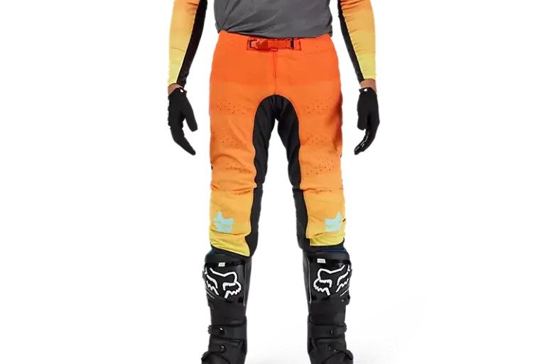 Flexair Grid Hose in Schwarz/Orange, getragen von einer Person mit Motocross-Stiefeln und Handschuhen, Vorderansicht.