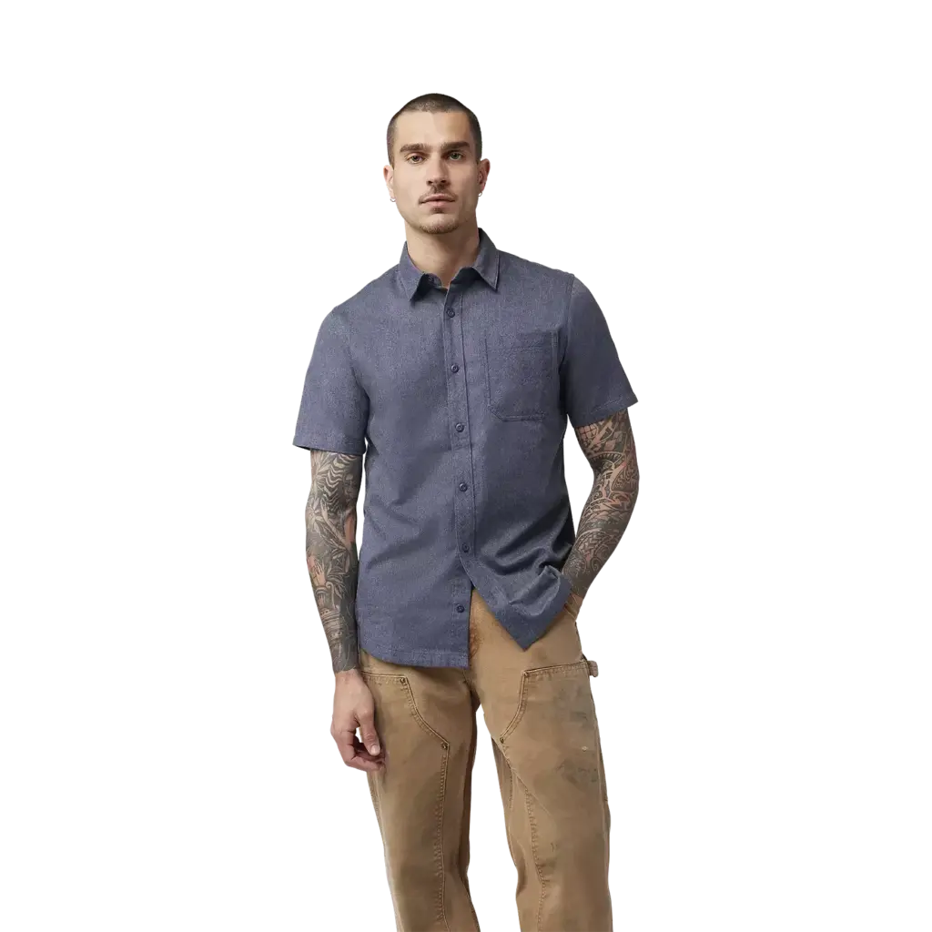 Ein Mann trägt ein kurzärmeliges, mitternachtsblaues Hemd mit Brusttasche, stehend vor weißem Hintergrund.