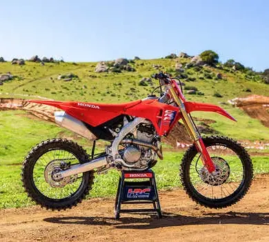 Honda CRF250R 2025 als Motocross-Motorrad vor einer Offroad-Strecke im Grünen