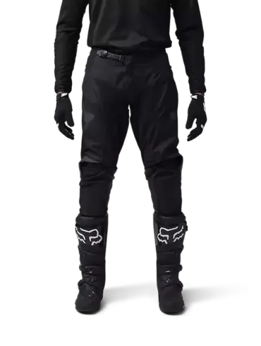 Motocross-Fahrer in schwarzer FOX 180 Blackout Crosshose mit Schutzstiefeln und Handschuhen.
