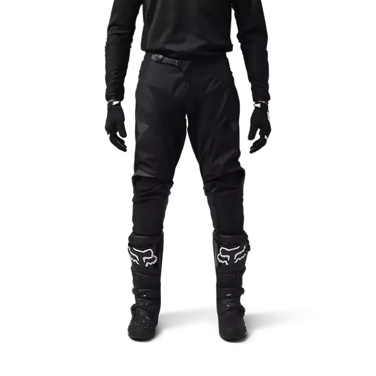 Motocross-Fahrer in schwarzer FOX 180 Blackout Crosshose mit Schutzstiefeln und Handschuhen.