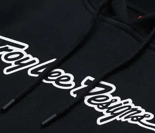 Schwarzer Troy Lee Designs Signature-Hoodie mit weißem Logo-Schriftzug, Detailansicht der Brustpartie.