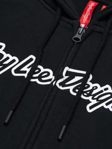 Nahaufnahme des schwarzen Troy Lee Designs Zip Up Hoodie Signature mit Reißverschluss und weißem Logo-Schriftzug.