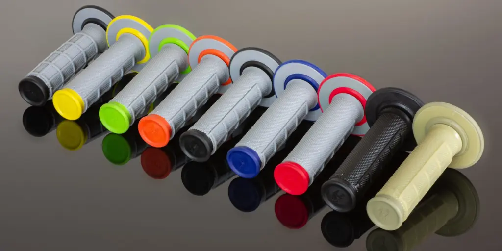 Mehrere Renthal Dual MX Motorradgriffe in bunten Farben nebeneinander auf schwarzem Untergrund.