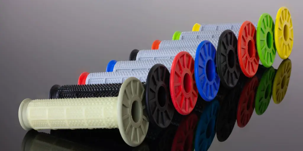 Mehrere MX/Enduro Motorradgriffe mit konischer Struktur und farbigen Flanschen, nebeneinander aufgereiht.