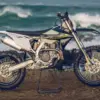 Triumph TF 450-E Enduro-Motorrad seitlich auf Felsen vor dem Ozean