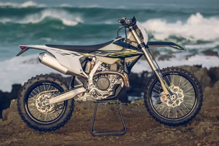 Triumph TF 450-E Enduro-Motorrad seitlich auf Felsen vor dem Ozean