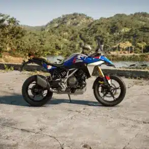 BMW F 450 GS Motorrad in blau, seitlich fotografiert, im Außenbereich mit Bergen und See im Hintergrund