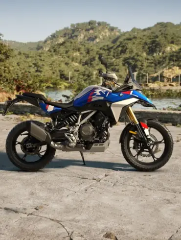 BMW F 450 GS Motorrad in blau, seitlich fotografiert, im Außenbereich mit Bergen und See im Hintergrund