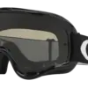 Oakley O-Frame MX Goggle in Schwarz mit dunklem Glas und breitem schwarzen Band mit weißem O-Logo, freigestellt.