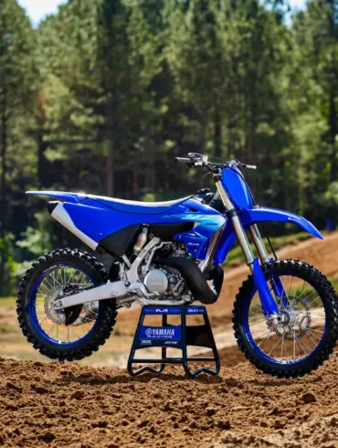 Yamaha YZ250 Motocross-Motorrad steht auf einer lehmigen Rennstrecke vor Waldkulisse.