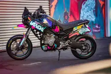 CFMOTO Ibex 450 Vandal als Supermoto-Stuntbike vor farbigem Graffiti und Garagentor.