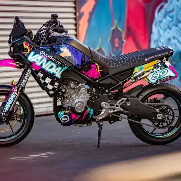 CFMOTO Ibex 450 Vandal als Supermoto-Stuntbike vor farbigem Graffiti und Garagentor.