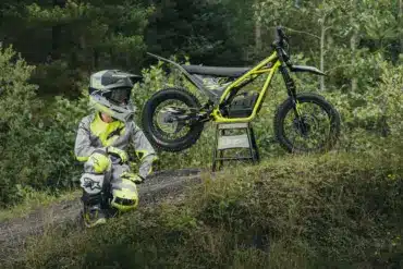 Ein Kind in Motocross-Schutzkleidung neben einer Triumph TXP-16 im Gelände.