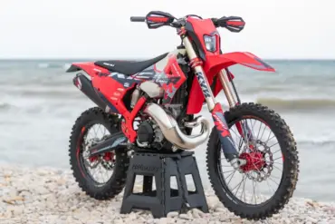 Rieju MR 300i PRO 2027 Enduro-Motorrad mit neuem Dekor auf einem Kiesstrand vor dem Meer.