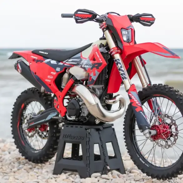 Rieju MR 300i PRO 2027 Enduro-Motorrad mit neuem Dekor auf einem Kiesstrand vor dem Meer.