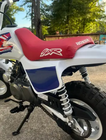 Klassische 1995 Honda Z50R mit rotem Sitz und weiß-blauer Verkleidung, im Freien abgestellt.