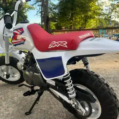 Klassische 1995 Honda Z50R mit rotem Sitz und weiß-blauer Verkleidung, im Freien abgestellt.