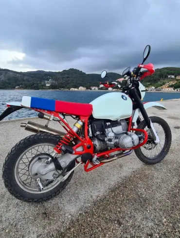 BMW Boxer Umbau von SWT-SPORTS mit rotem Rahmen und individuell gestalteter Frontpartie am Wasser stehend.