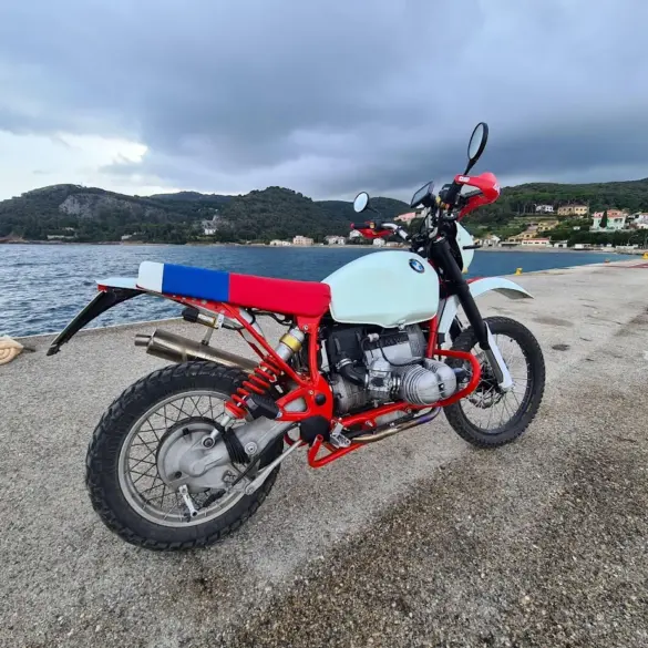 BMW Boxer Umbau von SWT-SPORTS mit rotem Rahmen und individuell gestalteter Frontpartie am Wasser stehend.