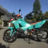 KTM 9X0 Rally Umbau mit hohem Kotflügel, Navigation Tower aus Carbon und schweizerischer Farbgebung, geparkt vor einer Berglandschaft.