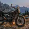 Triumph Scrambler 400 Escape Motorrad mit Campingausrüstung im Gebirge bei Abenddämmerung.