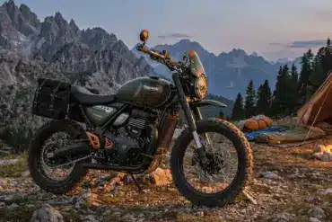 Triumph Scrambler 400 Escape Motorrad mit Campingausrüstung im Gebirge bei Abenddämmerung.
