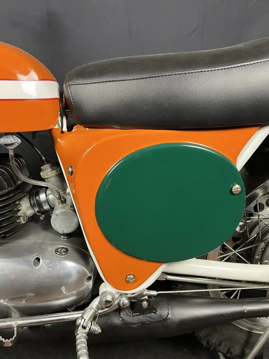 Detailfoto der restaurierten Sitzbank und Seitendeckel einer Montesa 250 GP, Baujahr 1968, in Orange und Grün.