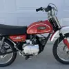 Seitenansicht einer Yamaha JT1 Mini Enduro von 1971 in Desert Orange, mit schwarzem Sitz und klassischen Offroad-Elementen.