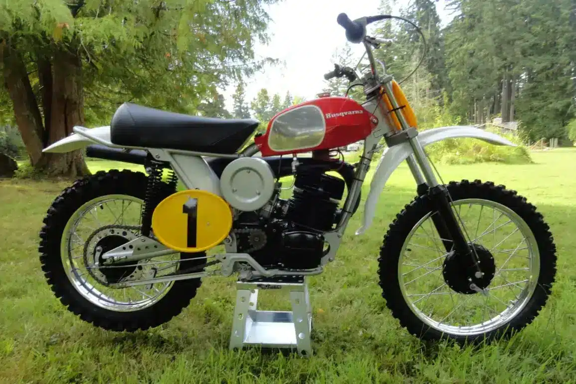 Motocross-Motorrad Husqvarna Pro-Fab Works 400CR Baujahr 1972, Seitenansicht im Freien, rote Tanklackierung, Startnummerntafel gelb mit schwarzer 1.