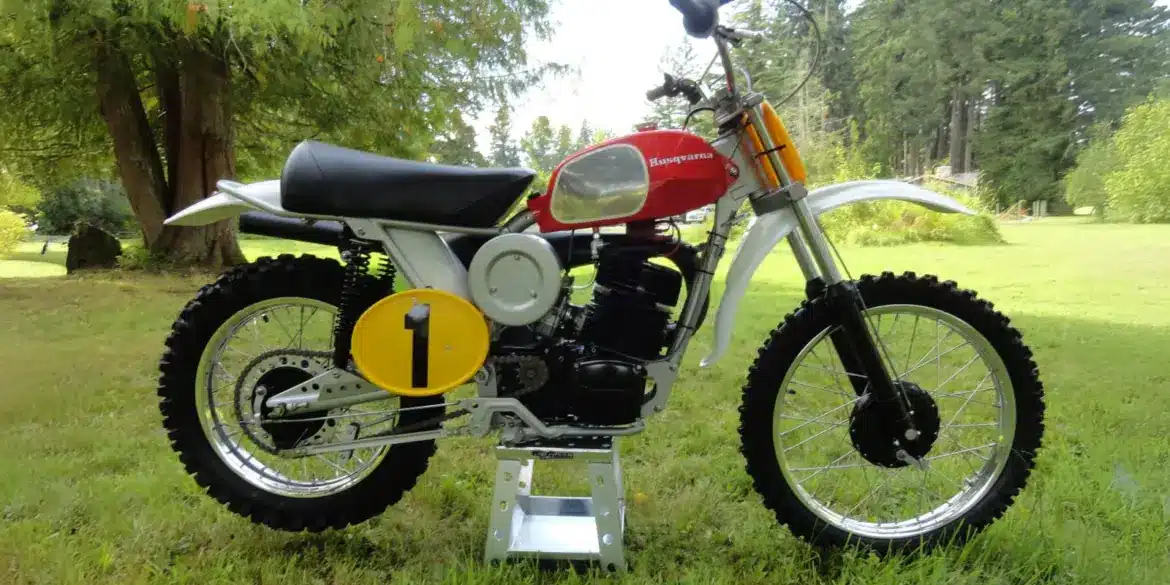 Motocross-Motorrad Husqvarna Pro-Fab Works 400CR Baujahr 1972, Seitenansicht im Freien, rote Tanklackierung, Startnummerntafel gelb mit schwarzer 1.