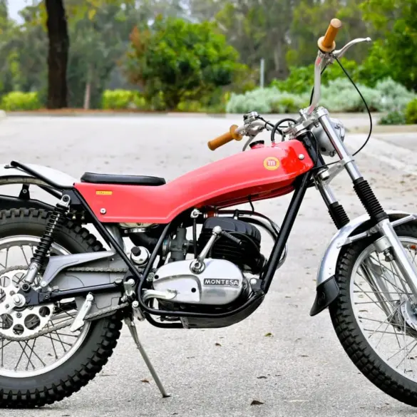 Seitenansicht einer roten 1972 Montesa Cota Enduro Trials mit Geländeprofil, abgestellt auf Asphalt.