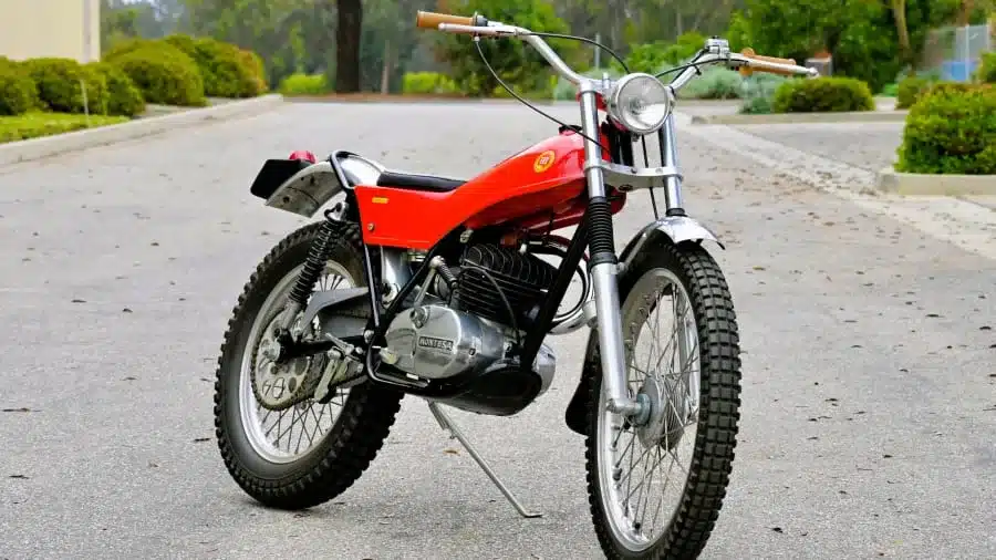 Montesa Cota 247 Enduro Trials Baujahr 1972 in orange und silber, ausgestellt auf einer Straße, Seitenansicht von vorn.
