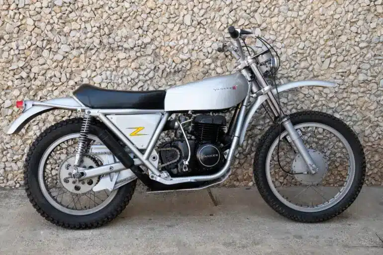 1972 Yankee Z500 Enduro Motorrad in silberner Lackierung seitlich vor einer Steinmauer.