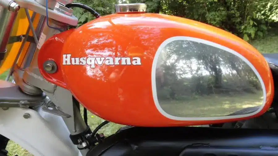 Roter Kraftstofftank mit Husqvarna-Logo an einem historischen Offroad-Motorrad aus den 1970er Jahren