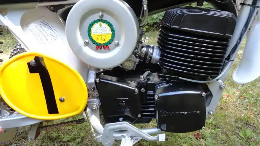 Nahaufnahme des Motors und Antriebs des Husqvarna Super Cycle 450 CR 3-Wheeler von 1973 mit gelber Startnummerntafel.