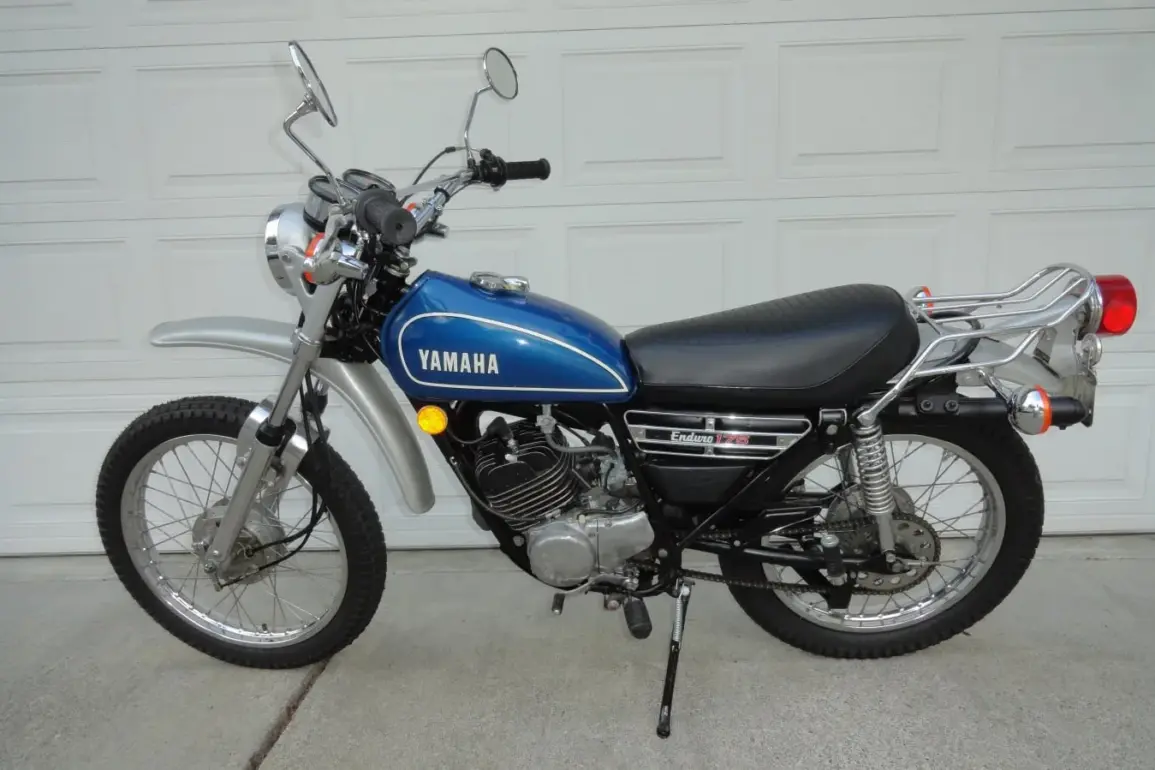 Seitenansicht einer blauen 1974 Yamaha DT175 Enduro mit verchromten Anbauteilen und Originalausstattung.