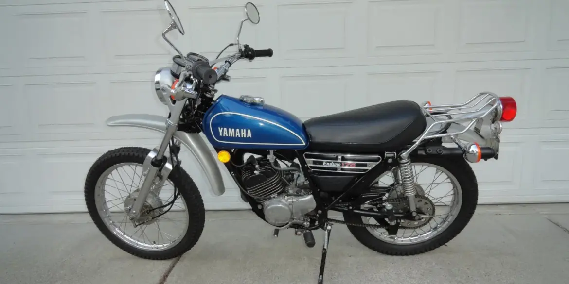 Seitenansicht einer blauen 1974 Yamaha DT175 Enduro mit verchromten Anbauteilen und Originalausstattung.