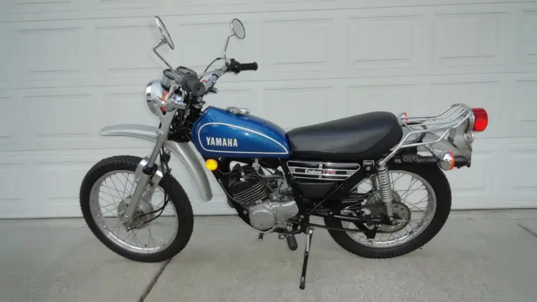 Seitenansicht einer blauen 1974 Yamaha DT175 Enduro mit verchromten Anbauteilen und Originalausstattung.