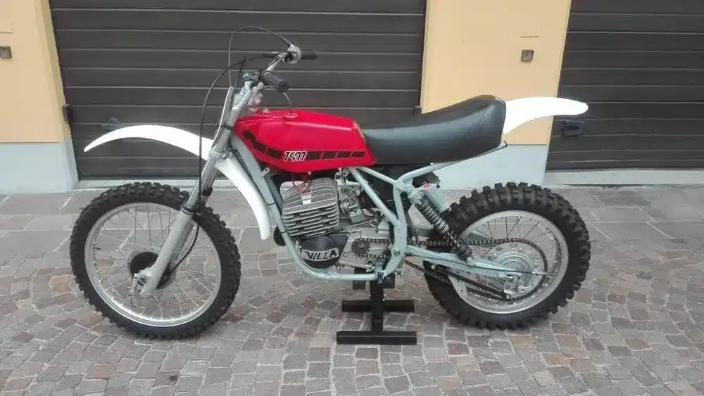 Seitenansicht einer restaurierten TGM 250 Cross Motore Villa von 1976 mit rotem Tank und grobstolligen Geländereifen.