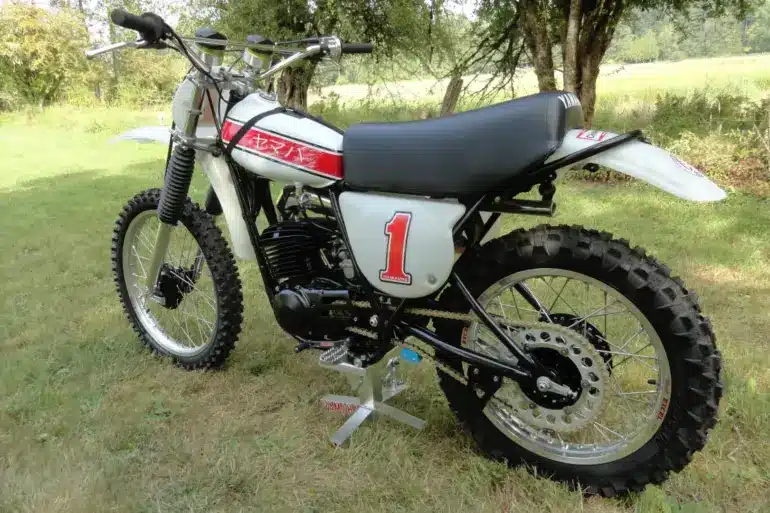 Klassische 1976 Yamaha YZ250C Motocross-Maschine mit Startnummer 1, Seitenansicht auf einer Wiese.