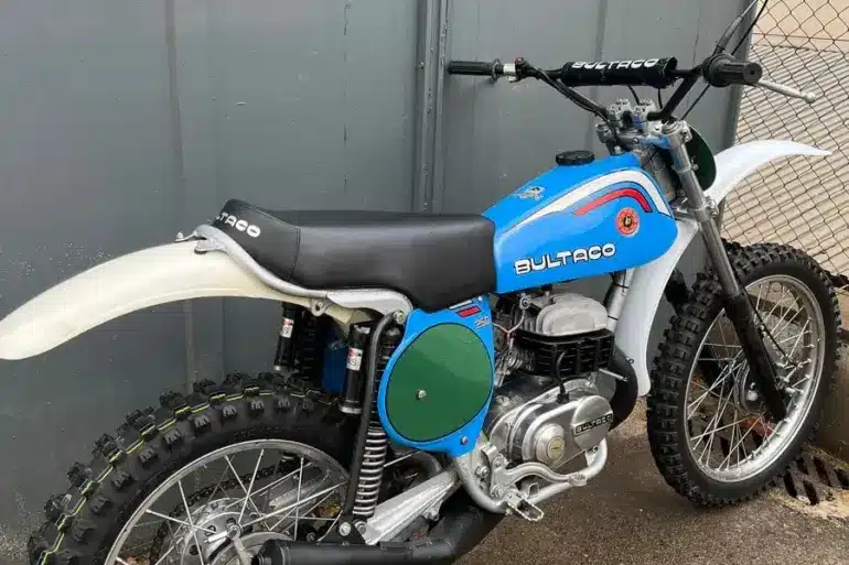 Restaurierte blaue Bultaco Pursang MK10 250cc von 1977, Seitenansicht vor grauer Wand.